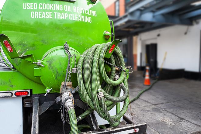 a professional plumber using a pump to empty a grease trap in Berlin Center OH